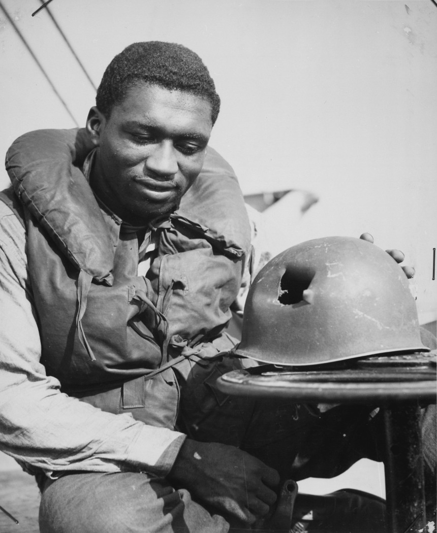 uscg Charles Tyner, Fireman First Class, inspects his helmet hit by shrapnel during the Allied landings in southern France. 1944.