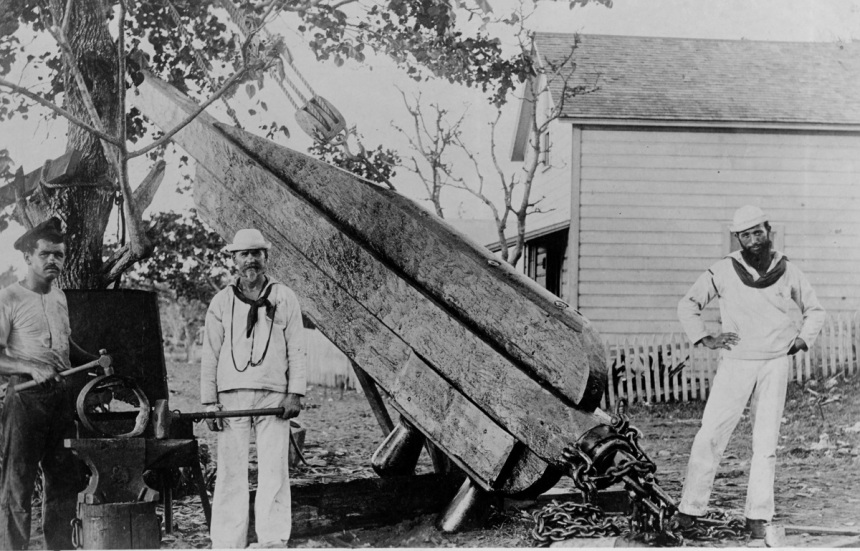Jury rudder being made for use in the ship's voyage to Hawaii to receive repairs for damage received during the 15-16 March 1889 hurricane. Probably taken at Apia, Upolu, Samoa, circa April-May 1889. The men present are (from left to right) the blacksmith's helper, blacksmith and carpenter's mate who built the rudder as designed and supervised by Rear Admiral Lewis A. Kimberly, USN. U.S. Naval History and Heritage Command Photograph. NH 63405