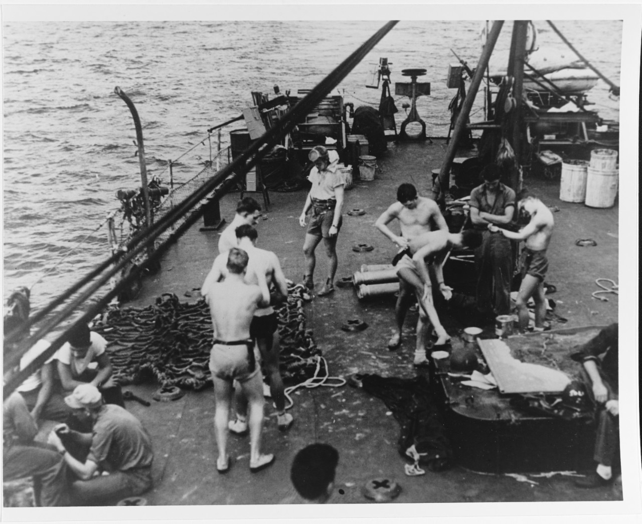 Okinawa UDT members daubed aluminum paint on their bodies as camouflage to throw off Japanese marksmen. Photographed on the fantail of a fast transport (APD), circa Spring 1945 80-G-274695